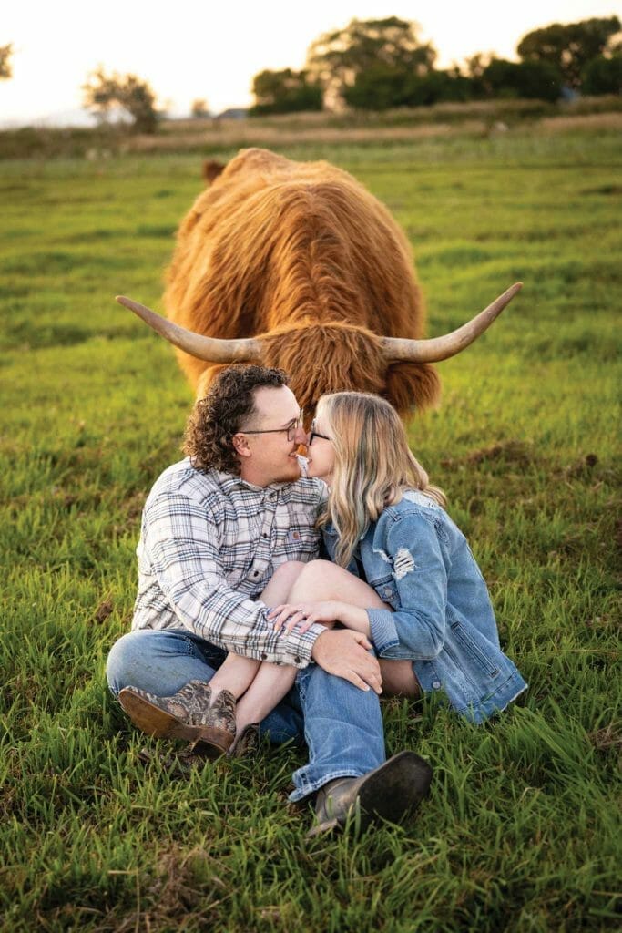 Highland Cow posed with Spencer & Karli Ivey at Fold of Liberty Farms in west Spanish Fork.