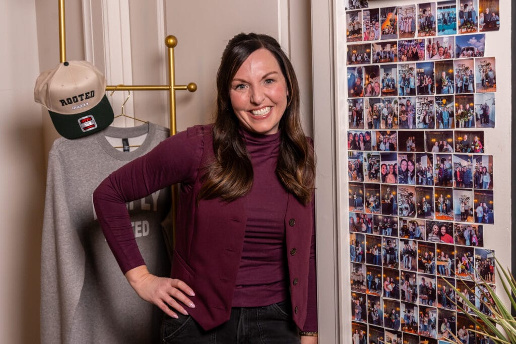 Kami Asay at Deeply Rooted by the picture wall. 